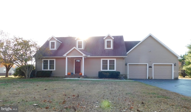 cape cod home with a front yard and a garage