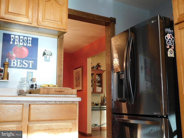 kitchen featuring light brown cabinetry, wood-type flooring, and stainless steel refrigerator with ice dispenser