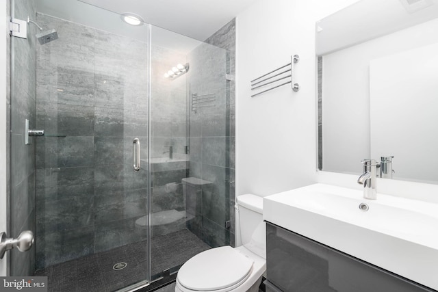 bathroom featuring vanity, toilet, and a shower with shower door