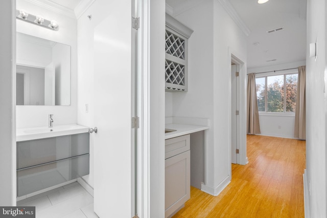 corridor featuring sink, crown molding, and light hardwood / wood-style flooring