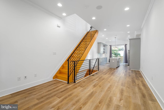 hall with light wood-type flooring and ornamental molding