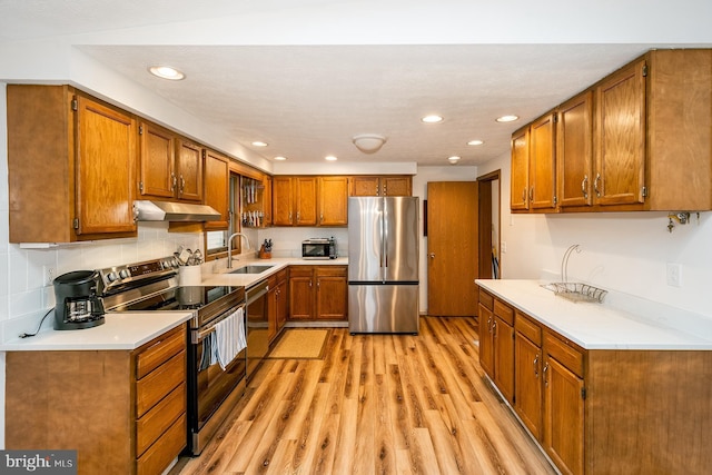 kitchen featuring backsplash, sink, appliances with stainless steel finishes, and light hardwood / wood-style flooring