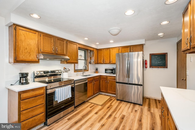 kitchen featuring sink, stainless steel appliances, a textured ceiling, and light hardwood / wood-style floors