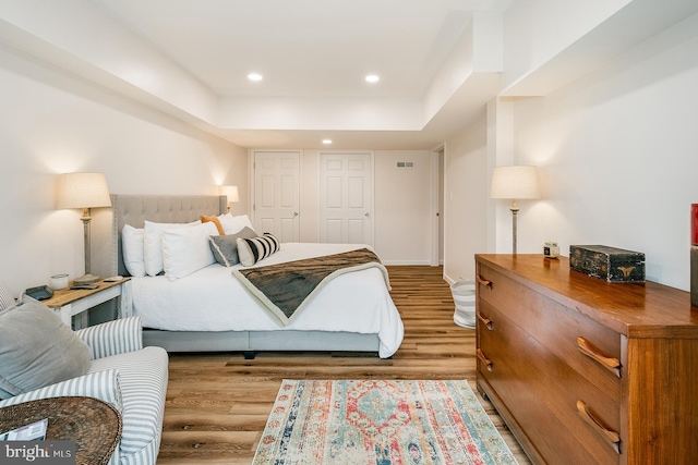 bedroom with wood-type flooring and a tray ceiling