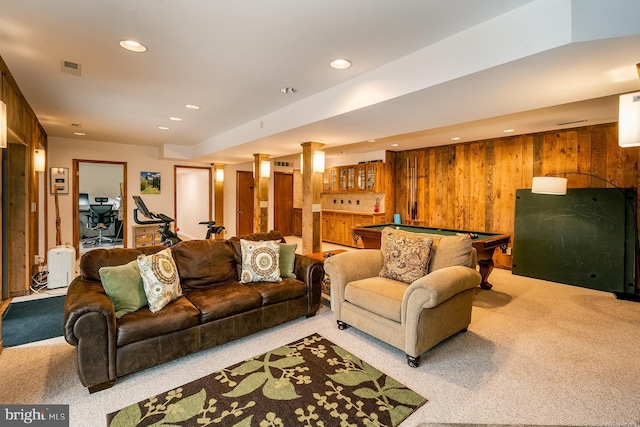 carpeted living room with bar area, pool table, and wood walls