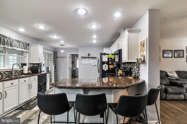 kitchen with white cabinets, dark hardwood / wood-style floors, black appliances, and tasteful backsplash