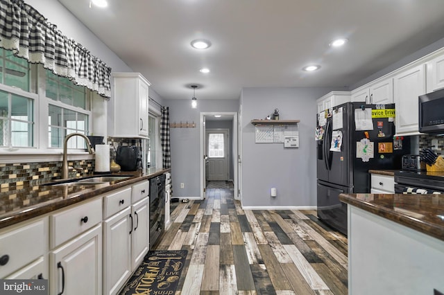 kitchen featuring decorative backsplash, dark hardwood / wood-style flooring, black appliances, sink, and white cabinets