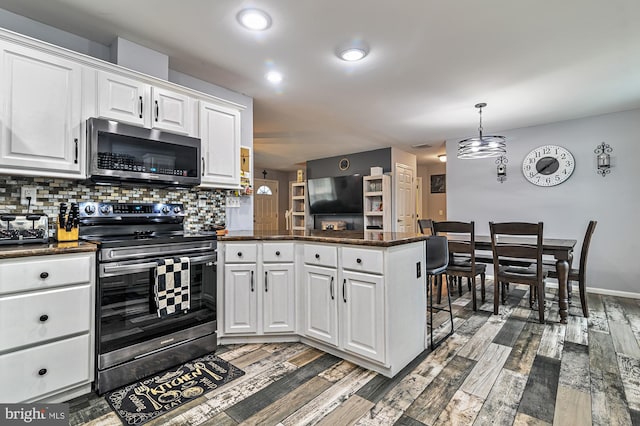 kitchen featuring white cabinets, appliances with stainless steel finishes, kitchen peninsula, and tasteful backsplash