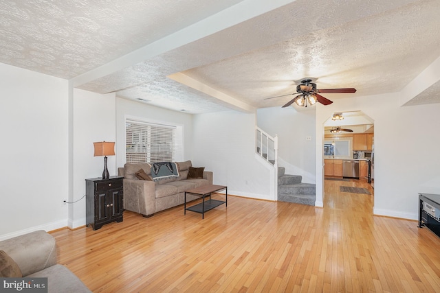 living room featuring ceiling fan, light hardwood / wood-style floors, and a textured ceiling