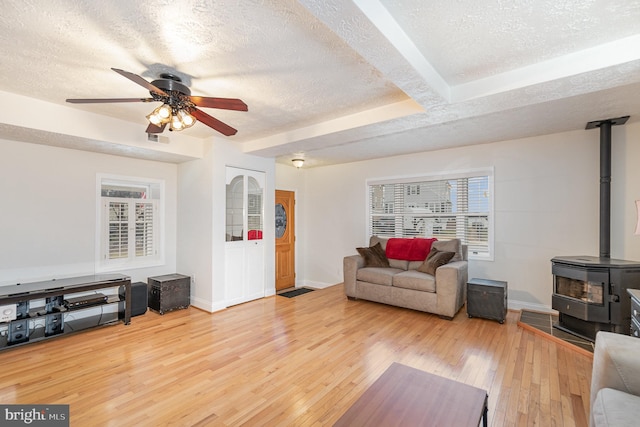 living room featuring wood-type flooring, a textured ceiling, and a wood stove