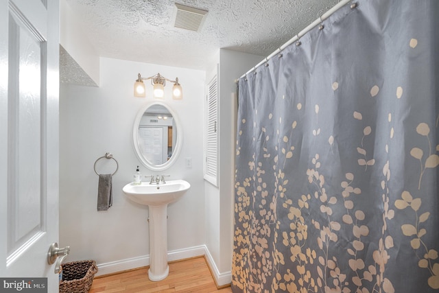 bathroom with hardwood / wood-style flooring, sink, and a textured ceiling