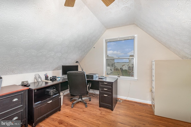 office space featuring a textured ceiling, light hardwood / wood-style floors, vaulted ceiling, and ceiling fan