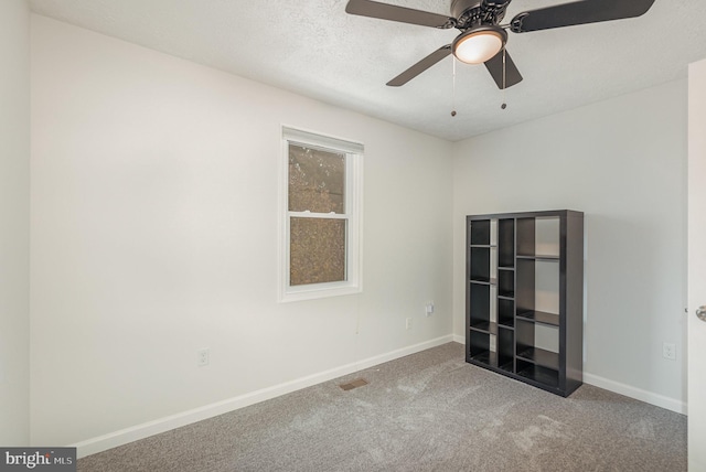 carpeted spare room with ceiling fan and a textured ceiling