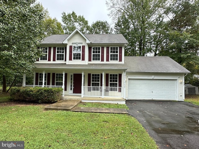 colonial inspired home with covered porch, a front yard, and a garage