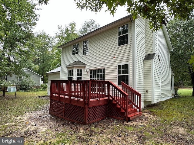 back of house featuring a lawn and a wooden deck