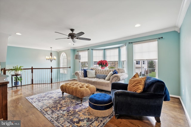 living room featuring ceiling fan with notable chandelier, light wood-type flooring, and ornamental molding