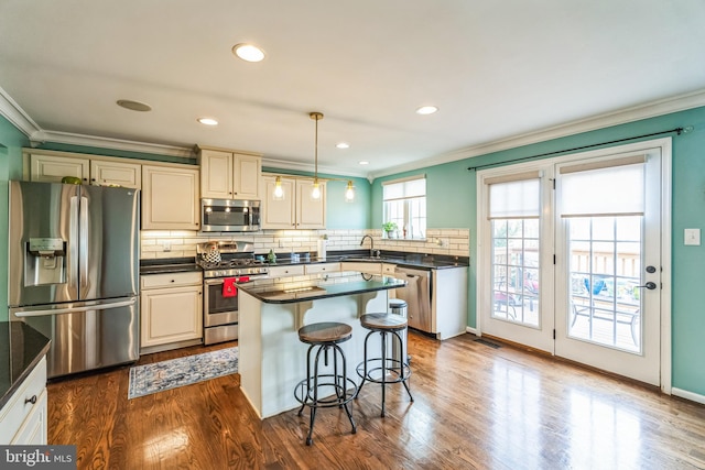 kitchen with pendant lighting, dark hardwood / wood-style floors, ornamental molding, a kitchen island, and stainless steel appliances