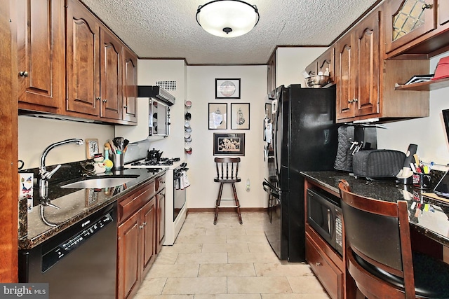 kitchen with sink, black appliances, a textured ceiling, and dark stone counters