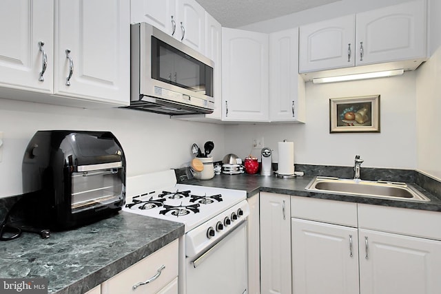 kitchen featuring white cabinets, white gas range oven, a textured ceiling, and sink