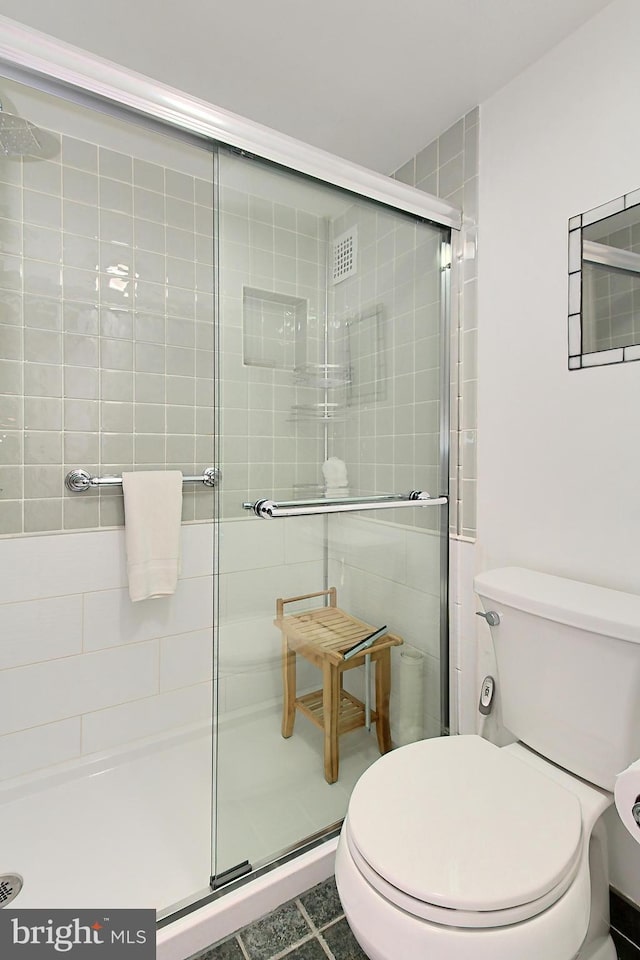 bathroom with toilet, an enclosed shower, and tile patterned flooring