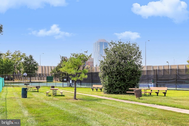 view of property's community featuring tennis court and a lawn