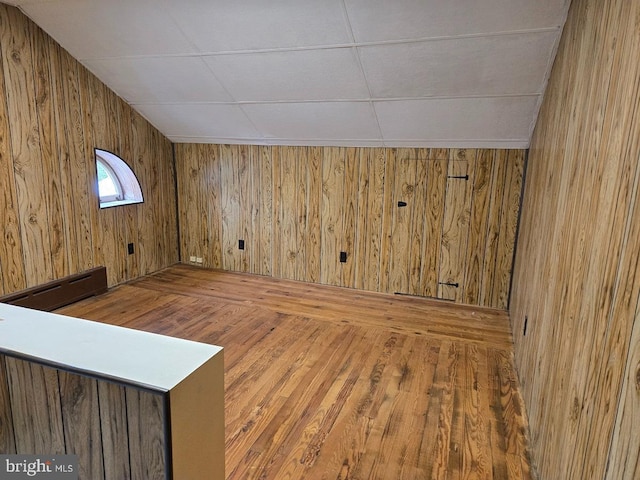 interior space featuring hardwood / wood-style floors, wood walls, and a baseboard heating unit