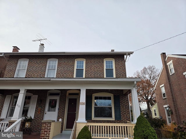 view of front of home with a porch and brick siding