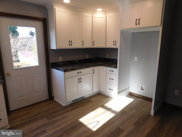 kitchen with white cabinets, dark stone counters, and dark hardwood / wood-style floors