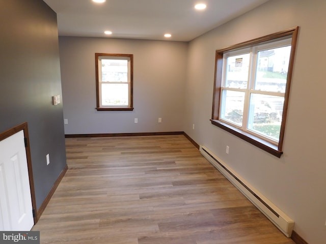 unfurnished room with baseboard heating and light hardwood / wood-style flooring