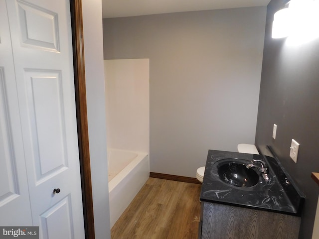 bathroom with vanity, toilet, wood-type flooring, and a tub