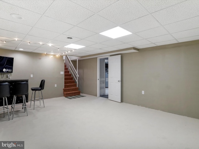 basement with bar area and a paneled ceiling