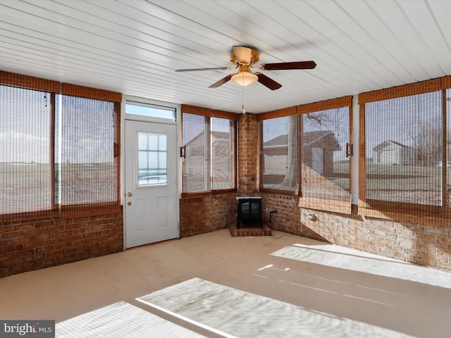 unfurnished sunroom with a wood stove, ceiling fan, and wood ceiling