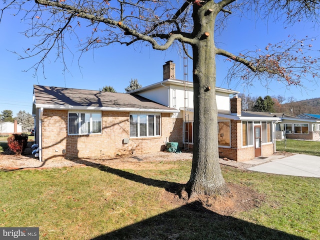 back of house with a lawn and a sunroom