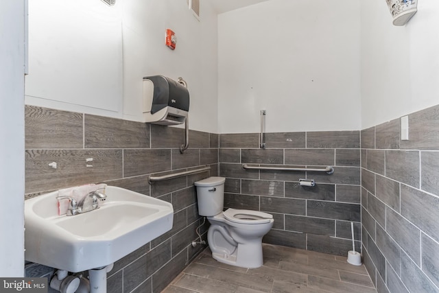 bathroom featuring sink, toilet, and tile walls