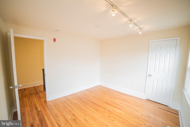 empty room with light hardwood / wood-style flooring and rail lighting