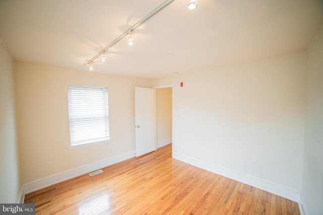 spare room featuring light wood-type flooring and rail lighting