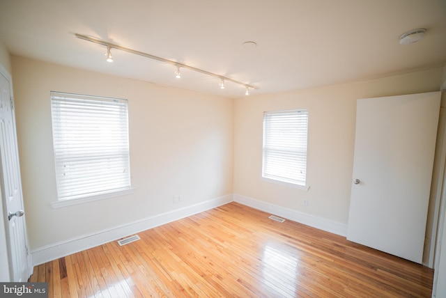 unfurnished room with light wood-type flooring and rail lighting