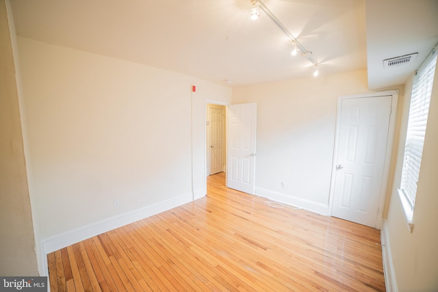 empty room featuring light hardwood / wood-style flooring and rail lighting