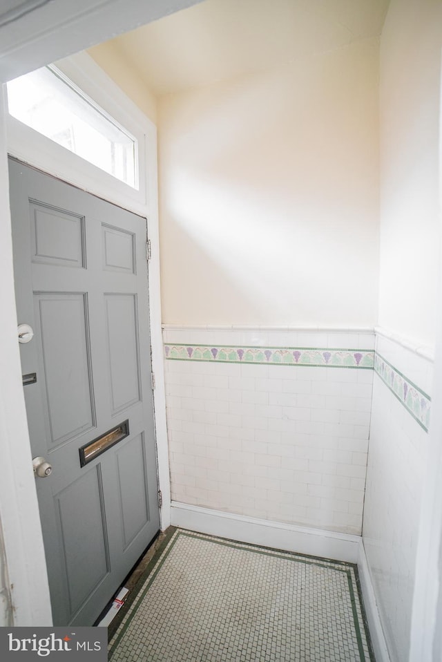 doorway to outside featuring tile patterned floors and tile walls