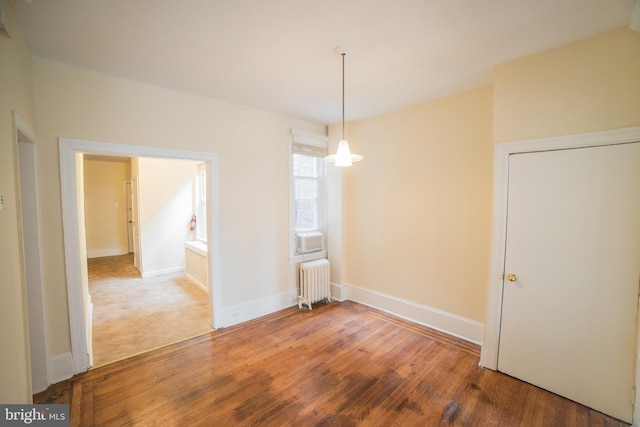 unfurnished dining area with wood-type flooring and radiator