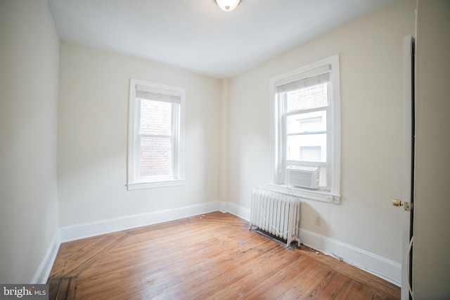 spare room with radiator heating unit, light hardwood / wood-style flooring, and a wealth of natural light