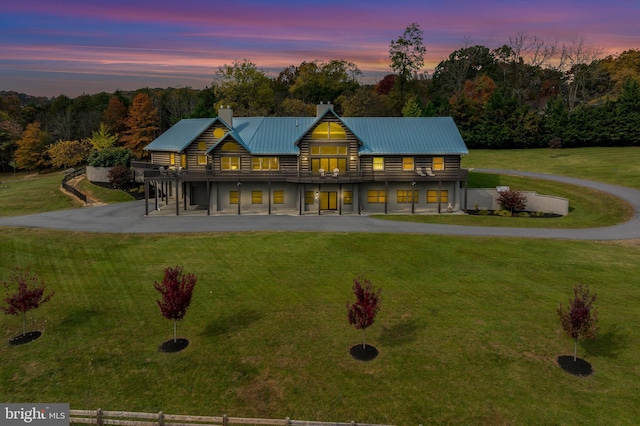 back house at dusk featuring a lawn