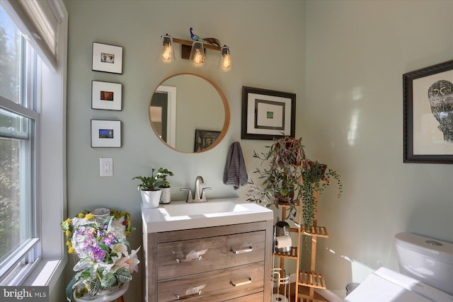 half bath featuring plenty of natural light, vanity, and toilet