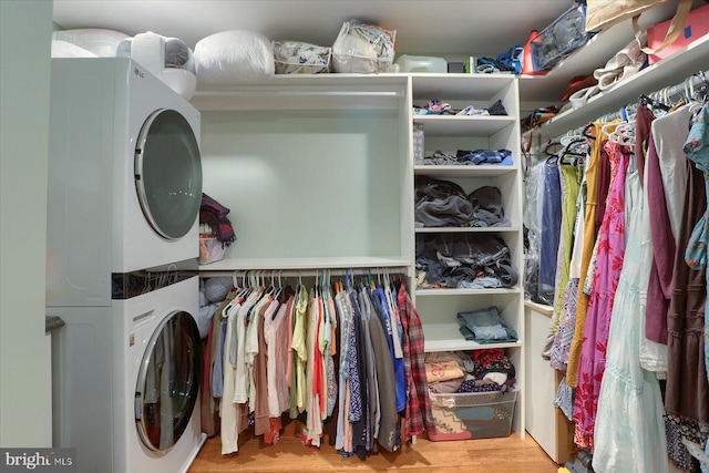 walk in closet with stacked washer / dryer and wood finished floors