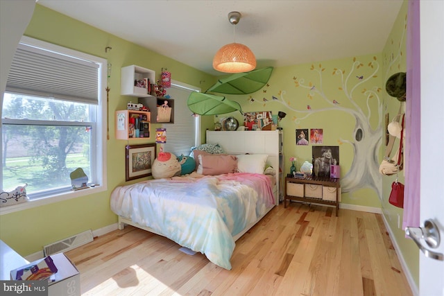 bedroom featuring light wood-style flooring, visible vents, and baseboards