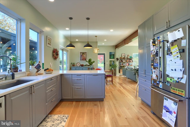 kitchen with gray cabinets, light countertops, light wood-style floors, freestanding refrigerator, and a sink