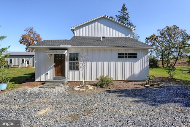 view of front facade with a shingled roof and a front yard