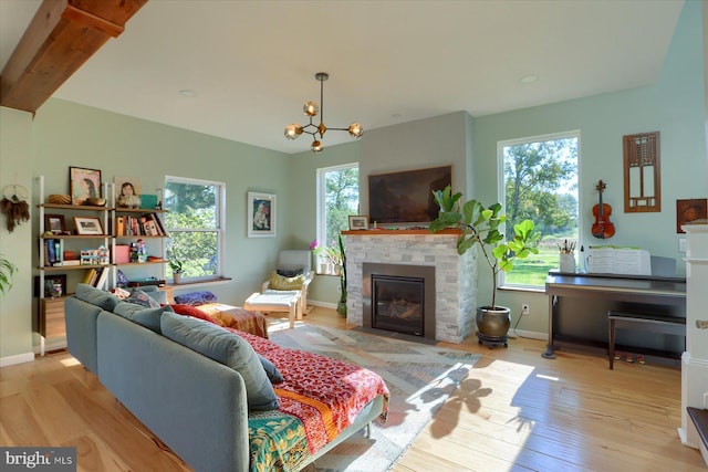 living room featuring a fireplace, wood finished floors, an inviting chandelier, and a healthy amount of sunlight