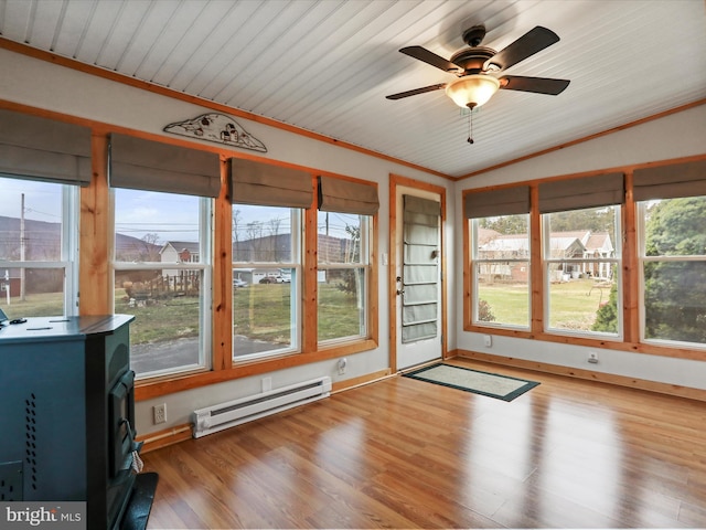 unfurnished sunroom featuring a wood stove, a baseboard heating unit, vaulted ceiling, and a wealth of natural light