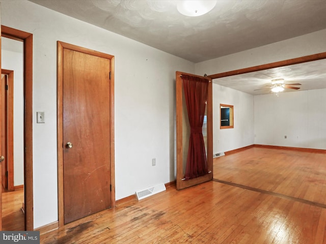 unfurnished room with a ceiling fan, visible vents, baseboards, and hardwood / wood-style flooring